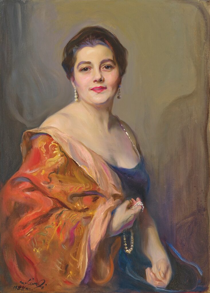 This is an oil painting of a european woman with short hair and an orange off the shoulder overcoat and blue dress. the painting is Portrait of Mrs Robert Celestin Guinness (Dickie) (1935) by Philip Alexius de László (Hungarian, 1869–1937)