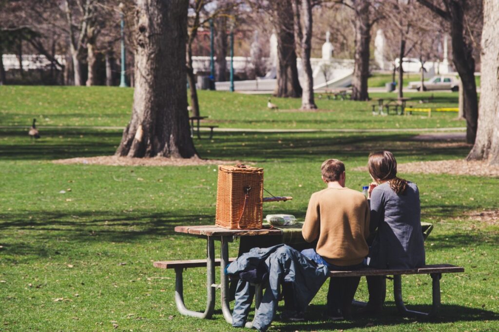 two individuals sitting at a bench in a park looking towards the background